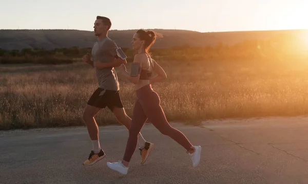 一对健康的年轻夫妇在城市街道上慢跑 背景是美丽的日出 高质量的照片 — 图库照片