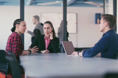 Ofiste yapılan beyin fırtınası sırasında çok kültürlü genç iş adamlarının ortak çalışma süreci. Resmi olarak giyinmiş çeşitli gençler tasarım projesinin geliştirilmesinde işbirliği yapıyor.
