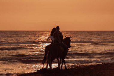 The family spends time with their children while riding horses together on a sandy beach. Selective focus. High quality photo