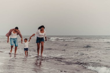 The family enjoys their vacation as they walk the sandy beach with their son. Selective focus . High quality photo