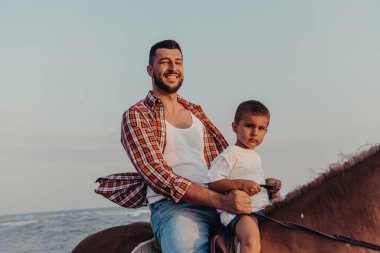 Baba ve oğul deniz kenarında at sürmekten hoşlanırlar. Seçici odaklanma. Yüksek kalite fotoğraf