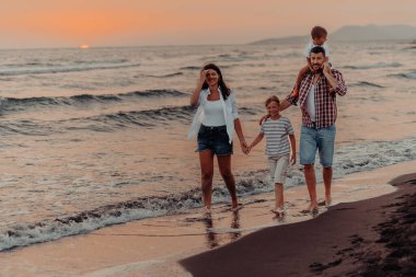 Aile toplantıları ve gün batımında sahilde sosyalleşme. Aile kumlu sahil boyunca yürür. Seçici odaklanma. Yüksek kalite fotoğraf