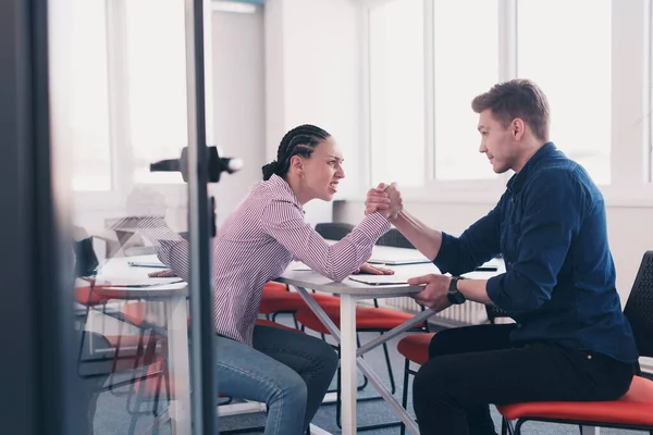 businesspeople, rivalry and people concept - businesswoman and businessman arm wrestling during corporate meeting in modern bright open space coworking startup business office. High quality photo