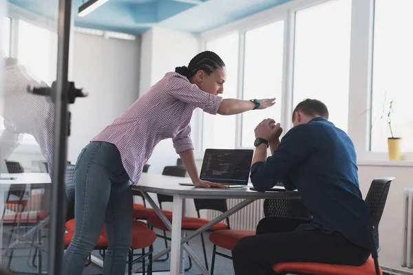 Emotional couple of young colleagues arguing in modern bright open space office. Business woman shouting at her sad man assistant in meeting room, copy space, side view. High quality photo