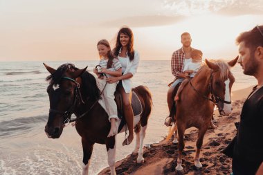 Aile kumlu bir sahilde birlikte ata binerken çocuklarıyla vakit geçirir. Seçici odaklanma. Yüksek kalite fotoğraf