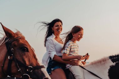 Anne ve kızı deniz kenarında birlikte ata binmekten hoşlanırlar. Seçici odaklanma. Yüksek kalite fotoğraf