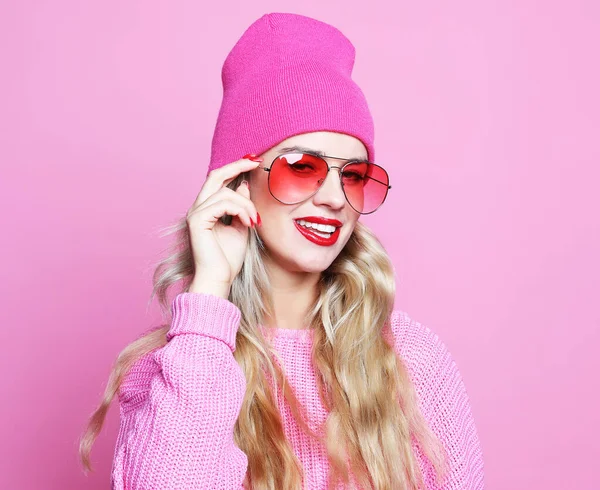 Stilvolles Modeporträt einer trendigen, lässigen jungen Frau in rosa Pulover und Hut, posierend über rosa Hintergrund. — Stockfoto