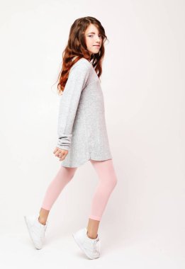 Beyaz arka plan üzerinde güzel küçük moda modeli kız. Studio poz sevimli gülümseyen kız portresi