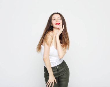 Yaşam tarzı, duygu ve insan konsepti: Genç, güzel, esmer kadın, günlük kıyafetler giyiyor, ligjt gri arka planda poz veriyor..