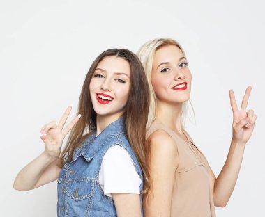 Yaşam tarzı, duygu ve insan konsepti: iki genç bayan arkadaş bir arada duruyor ve eğleniyorlar. Kameraya bakıyorum..