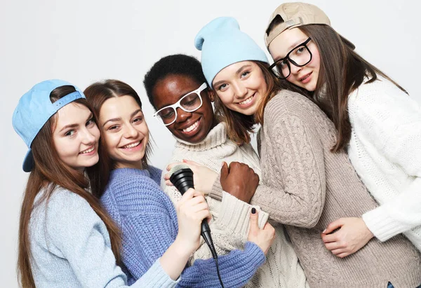 Pięć młodych wielorasowych kobiet w swetrach i kapeluszach z mikrofonem — Zdjęcie stockowe