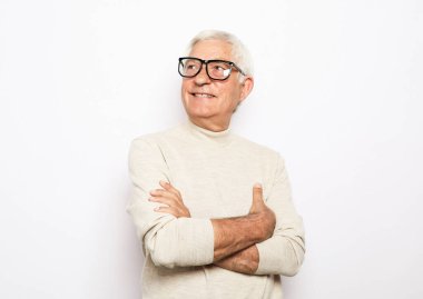 Yakışıklı, son sınıf öğrencisi, günlük giysiler içinde, gözlük takıyor, kollarını çapraz tutuyor ve beyaz arka planda tek başına duruyor..