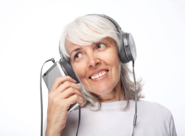 Mutlu bir son sınıf kadınının portresi kulaklıkla müzik dinlemektir. Beyaz arkaplanda izole.