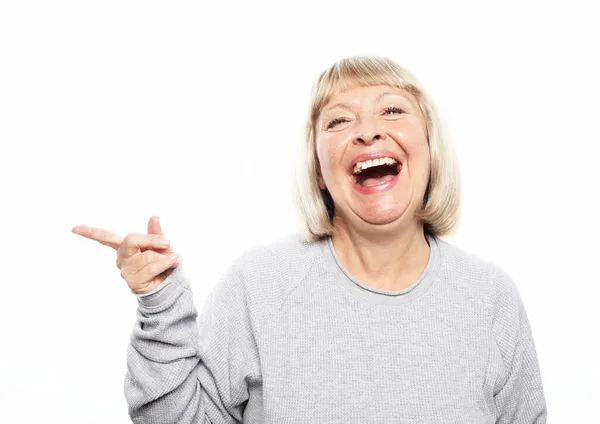 Mosolygó idős szőke nő hölgy 60-as éveiben alkalmi pulóver mutató mutatóujj félre a mock up másolás helyet — Stock Fotó
