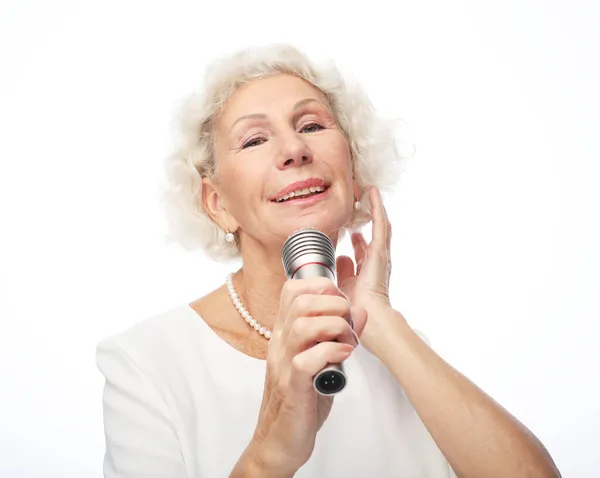 Felice vecchia donna che indossa camicia bianca che tiene un microfono e canta — Foto Stock