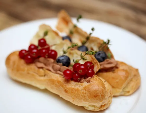 Eclairs mit frischen Beeren auf weißem Teller, handgemacht, kulinarisches Thema, Nahaufnahme — Stockfoto