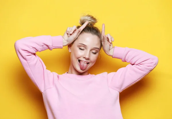Jovem mulher vestindo casual desgaste sobre amarelo fundo fazendo engraçado gesto com dedo sobre a cabeça como touro chifres — Fotografia de Stock