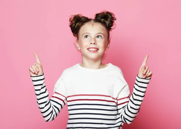 Niña divertida se sorprende y muestra sus pulgares hacia arriba, sobre un fondo rosa — Foto de Stock