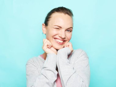 Çekici sarışın kadın gülüyor ve hayattan zevk alıyor. Mavi arka planda sıradan giyinmiş bir kız..