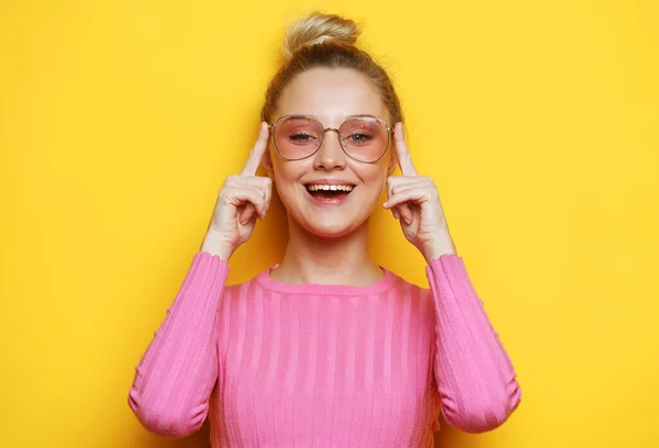 La encantadora rubia se ríe y disfruta de la vida. Chica vestida con suéter rosa sobre un fondo amarillo. — Foto de Stock