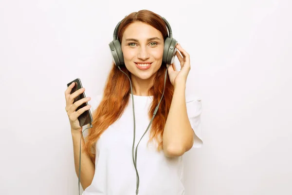 Style de vie et concept de personnes : jeune femme rousse avec écouteurs écoutant de la musique. — Photo