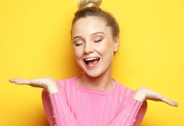 La encantadora rubia ríe y disfruta de la vida. Chica vestida con un jersey rosa posando sobre un fondo amarillo. — Foto de Stock