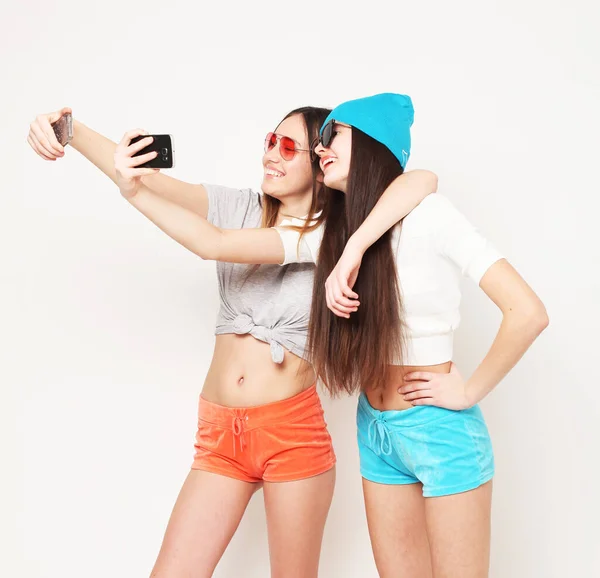 Két gyönyörű tinédzser együtt szórakozik, vicces arcokat vágnak, szelfit csinálnak.. — Stock Fotó