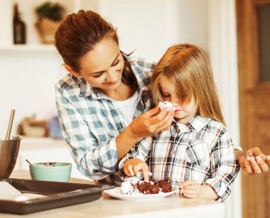 Anne ve 4 yaşındaki kız kurabiye pişiriyor.