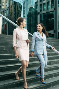 İş, insanlar ve başarı kavramı: iki kadın profesyonel ofise giderken projeyi tartışıyorlar. Şehirde iş kadınları dolaşıyor. Kurumsal iletişim kavramı