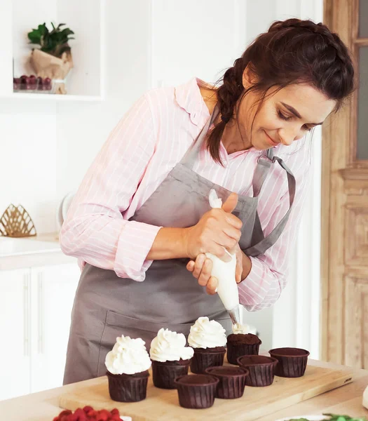 Fiatal nő cukrásztáska préselő krém cupcakes — Stock Fotó
