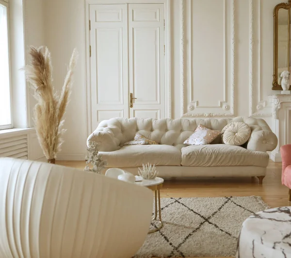 Velvet white and pink armchair with pillow next to sofa and coffee table. Elegant interior.