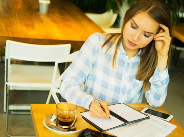 Zeki kadın fikirlerini yazıyor ve kafede kahve içiyor.