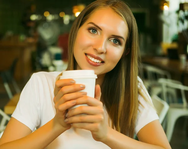 Усміхнена жінка в хорошому настрої з чашкою кави, сидячи в кафе . — стокове фото