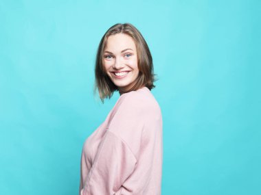 Güzel, gülümseyen, sarı saçlı, sıradan giyinmiş, kameraya bakarak mutlu olan bir kadın..