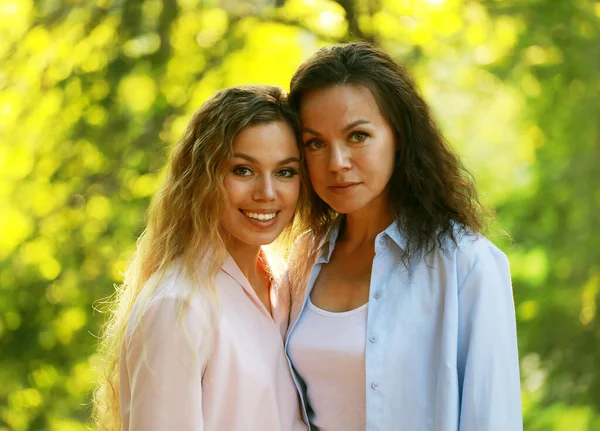 Mom and her adult daughter hold hands in a summer park — Stock Photo, Image