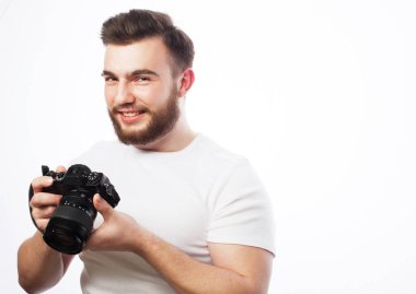 Genç sakallı bir erkek fotoğrafçı beyaz arka planda yalnız başına çektiği fotoğraflara bakıyor..