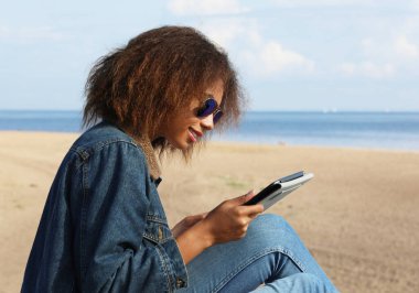 Genç bir afro kadın tablet kullanarak yeni bir ders alıyor..