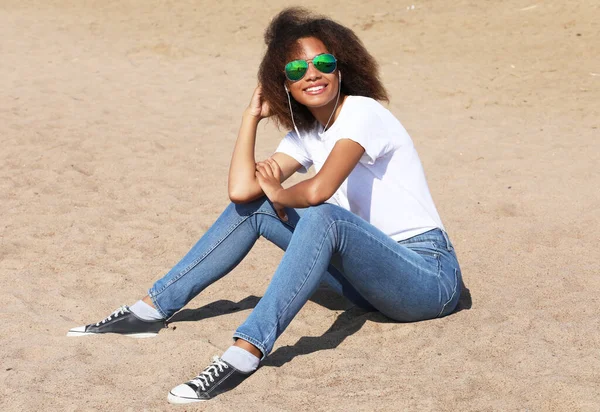 Geweldig afro amerikaanse jonge vrouw in zonnebril luisteren naar muziek in hoofdtelefoon. — Stockfoto