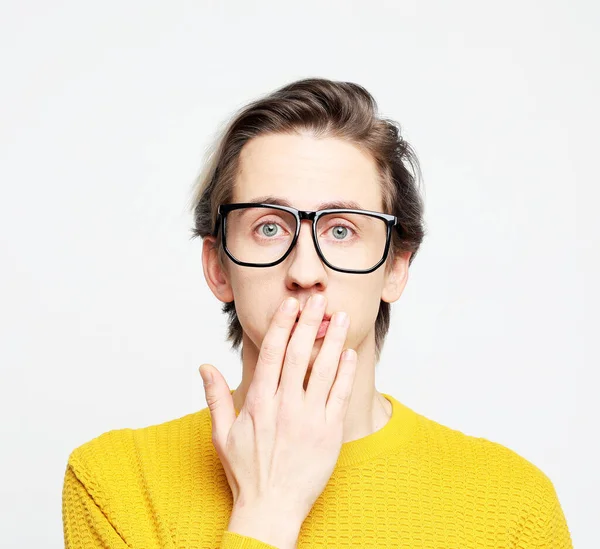 Geschokt jongeman draagt gele trui bedekken zijn mond met handen over witte grijze achtergrond. — Stockfoto