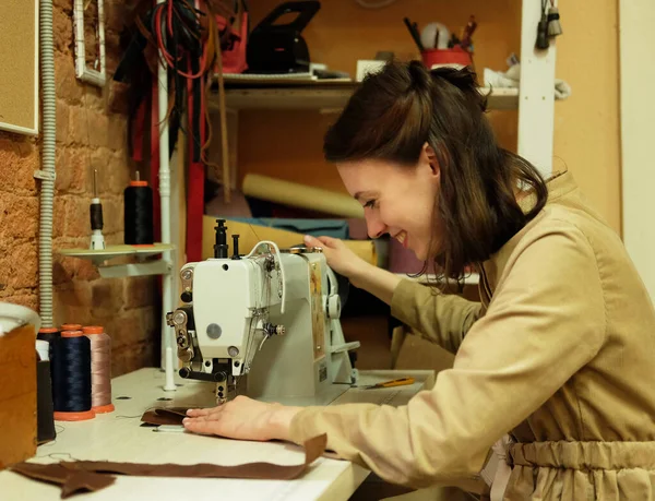 Giovane donna cuce i dettagli di una borsa su una macchina da cucire — Foto Stock