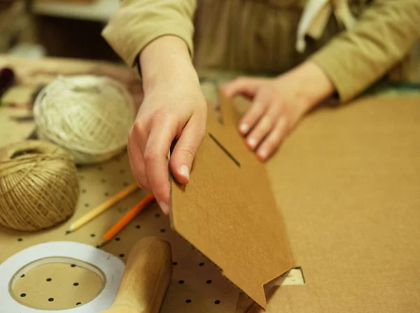 Une jeune femme plie une boîte en carton pour emballer des marchandises pour un client. — Photo