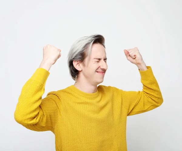 Jonge man dragen van gele trui staan over geïsoleerde witte achtergrond zeer gelukkig en enthousiast doen winnaar gebaar met armen opgeheven — Stockfoto