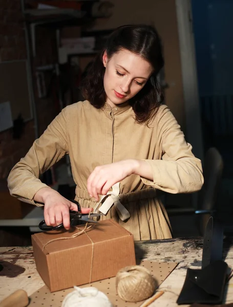 Giovane donna piega scatola di imballaggio nel laboratorio di cucito — Foto Stock