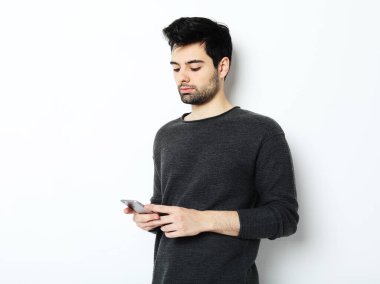 Cep telefonu kullanan gülümseyen genç sakallı adam.