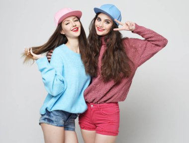 İki neşeli genç arkadaş gri arka planda birlikte vakit geçiriyorlar..