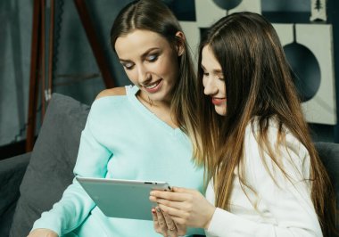 İki genç kadın tablette bir şeyler okuyor, online alışveriş yapıyor, öğreniyorlar..