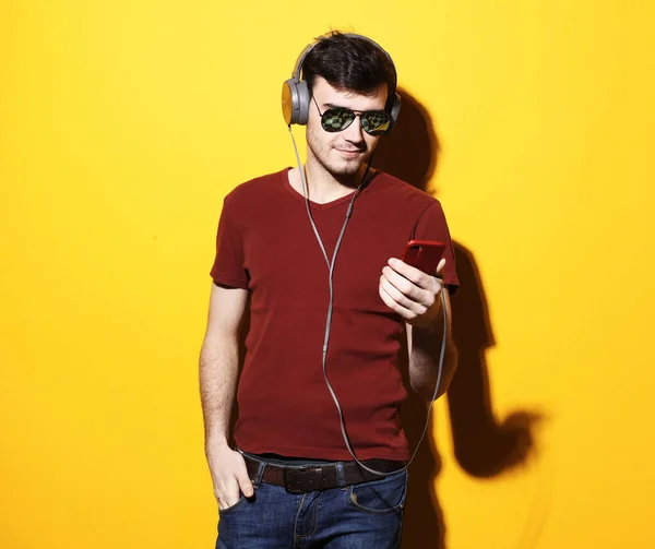 Jonge knappe man draagt casual t-shirt en zonnebril luisteren naar muziek in hoofdtelefoon — Stockfoto