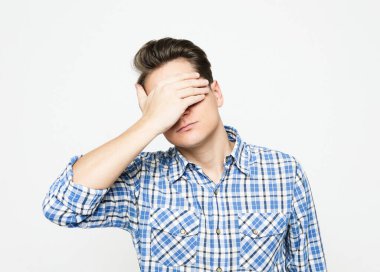 Gri arka planda elleri kapalı genç yakışıklı adam gözlerini kapatıyor.