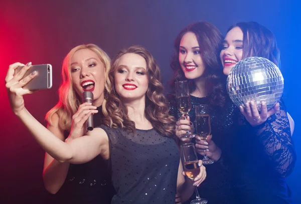 Close-up shot of group of laughing women wearing black dresses having party, take selfie with smartphone — Stock Photo, Image