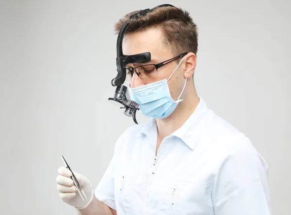 Joven dentista masculino con bata de laboratorio blanca y máscara que sostiene instrumentos dentales —  Fotos de Stock